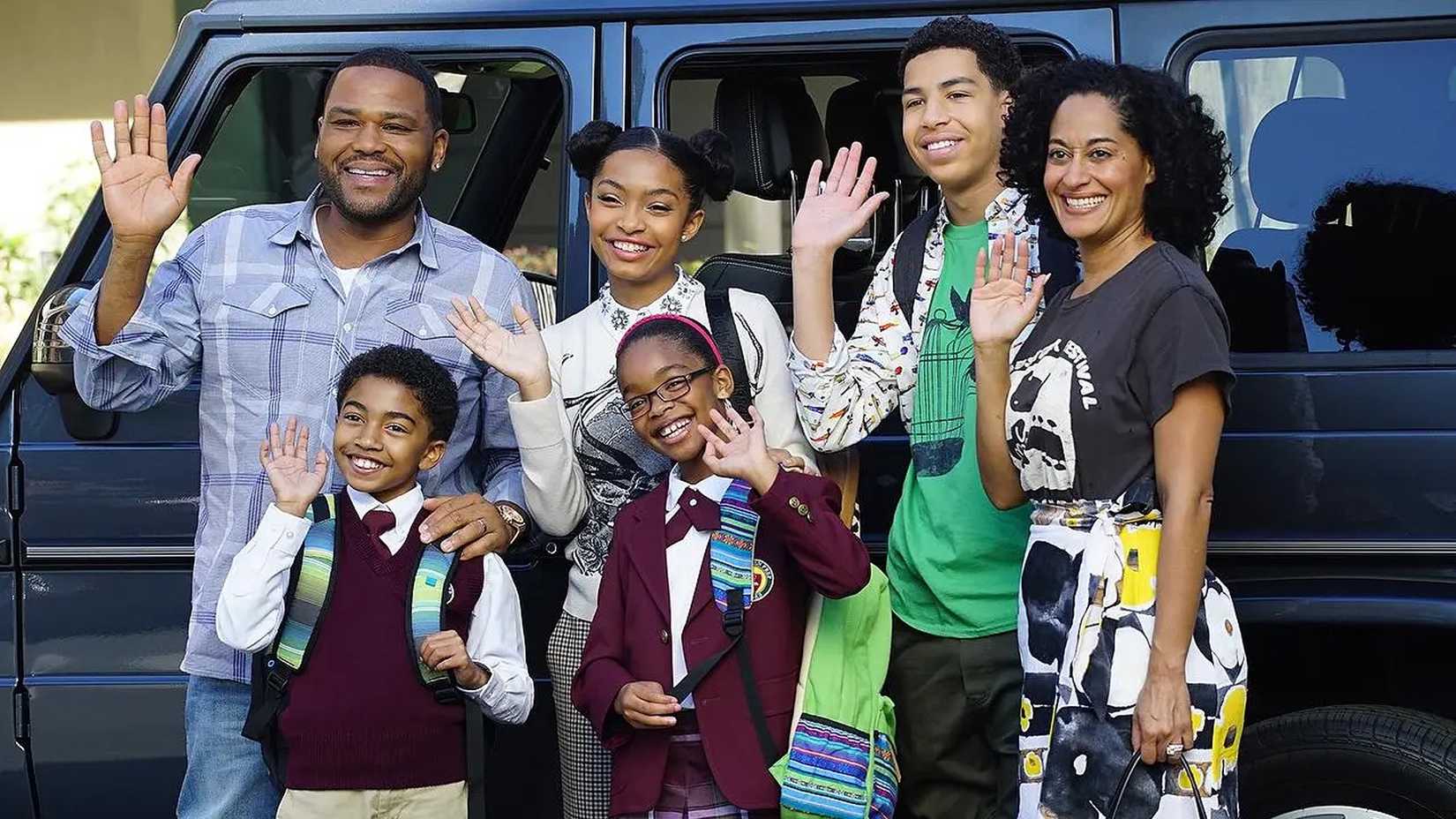 The Johnson Family waving in front of their car in Black-ish.