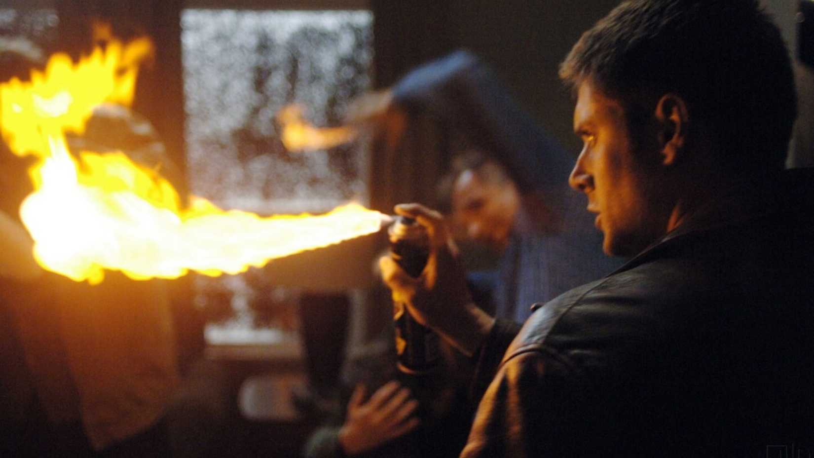 Dean Winchester holds a can of hairspray with a flame coming out of it