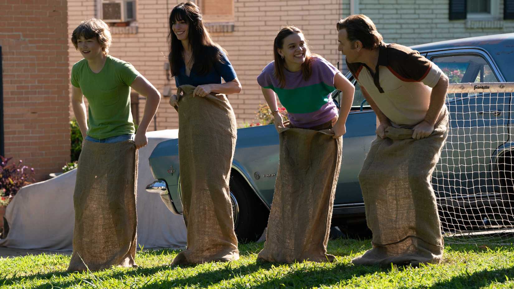 Christian Convery as Brian, Anne Hathaway as Denise, Maisy Stella as Audrey and Ewan McGregor as Greg Participating In A Sack Race In The End Of Oak Street