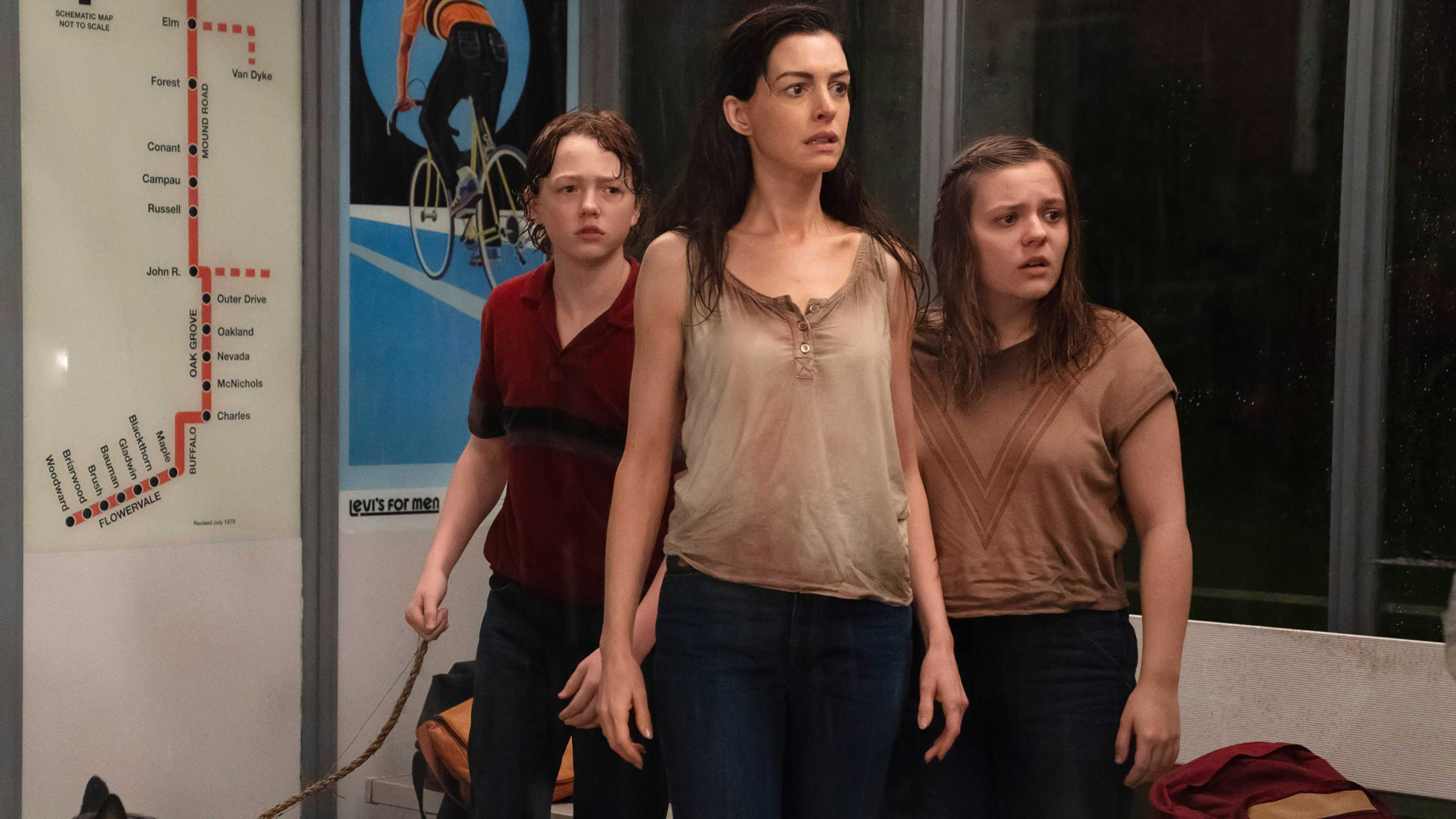 Christian Convery's Brian, Anne Hathaway's Denise and Maisy Stella's Audrey looking worried at a bus stop in The End of Oak Street