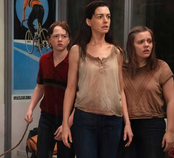Christian Convery's Brian, Anne Hathaway's Denise and Maisy Stella's Audrey looking worried at a bus stop in The End of Oak Street