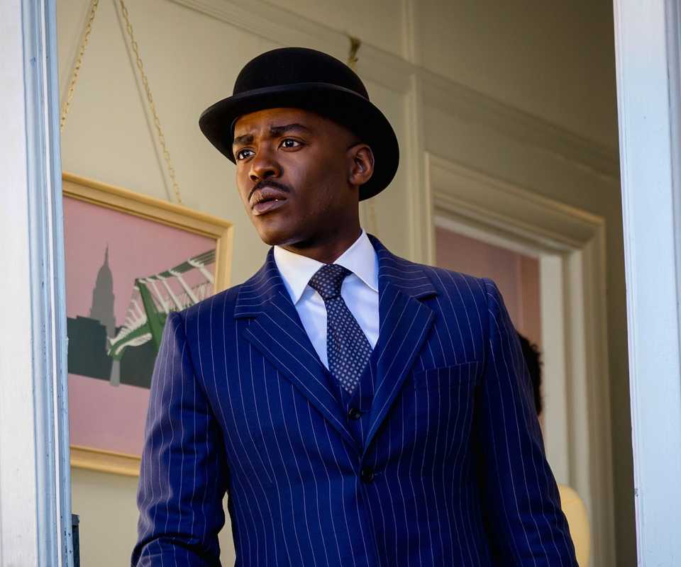 The Fifteenth Doctor in a doorway wearing a blue striped suit and bowler hat