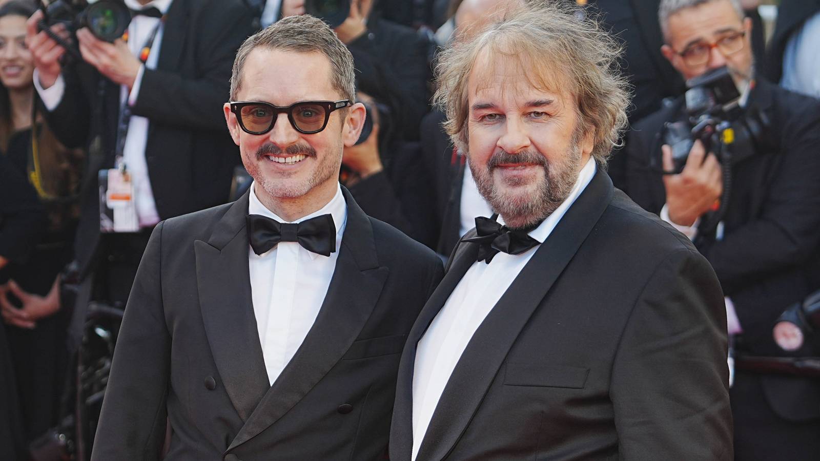 Elijah Wood and Peter Jackson smile for the cameras while attending a red carpet
