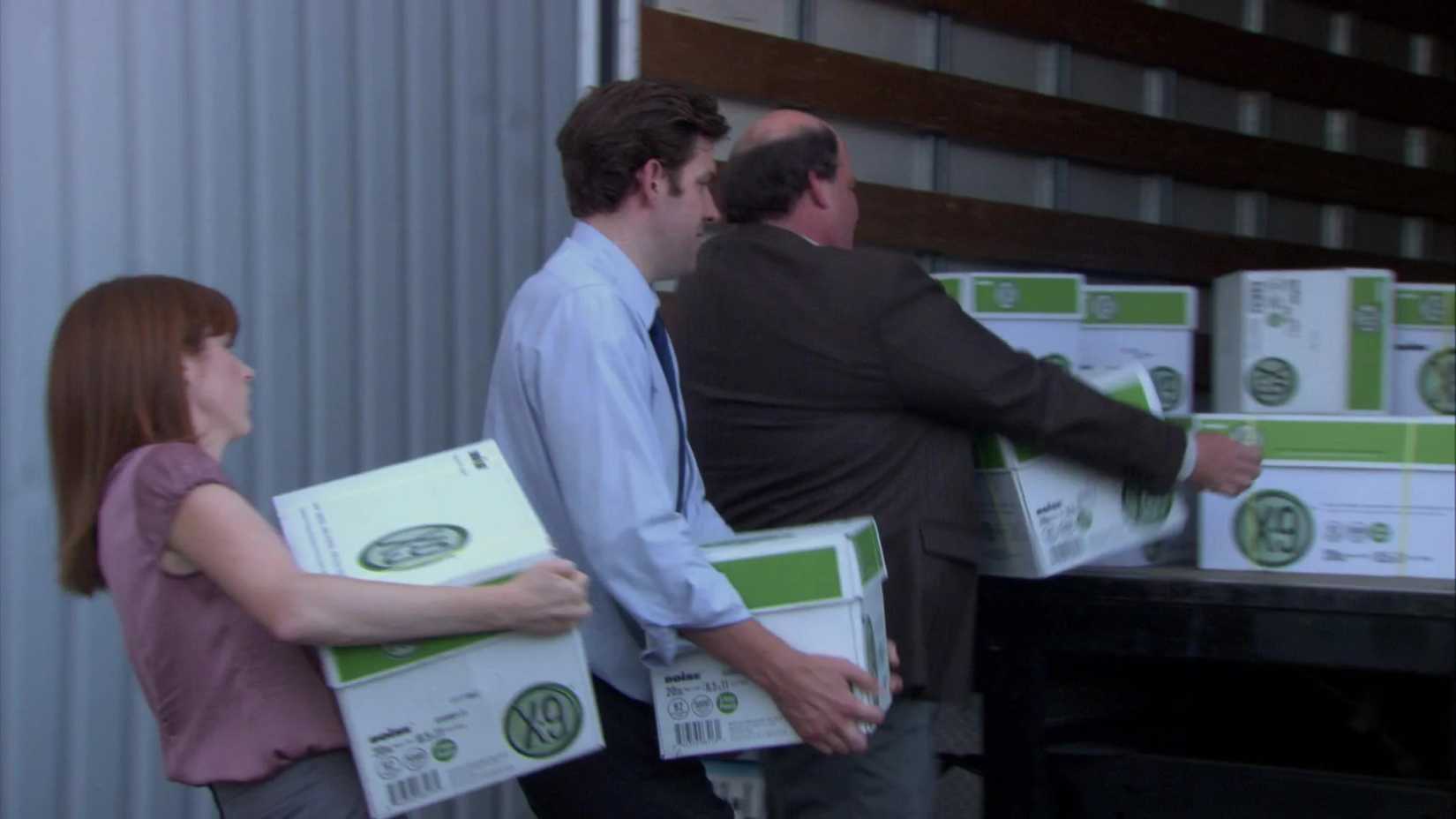 Erin (Ellie Kemper), Jim (John Krasinski), and Kevin (Brian Baumgartner) loading a truck with paper in The Office, Lotto.