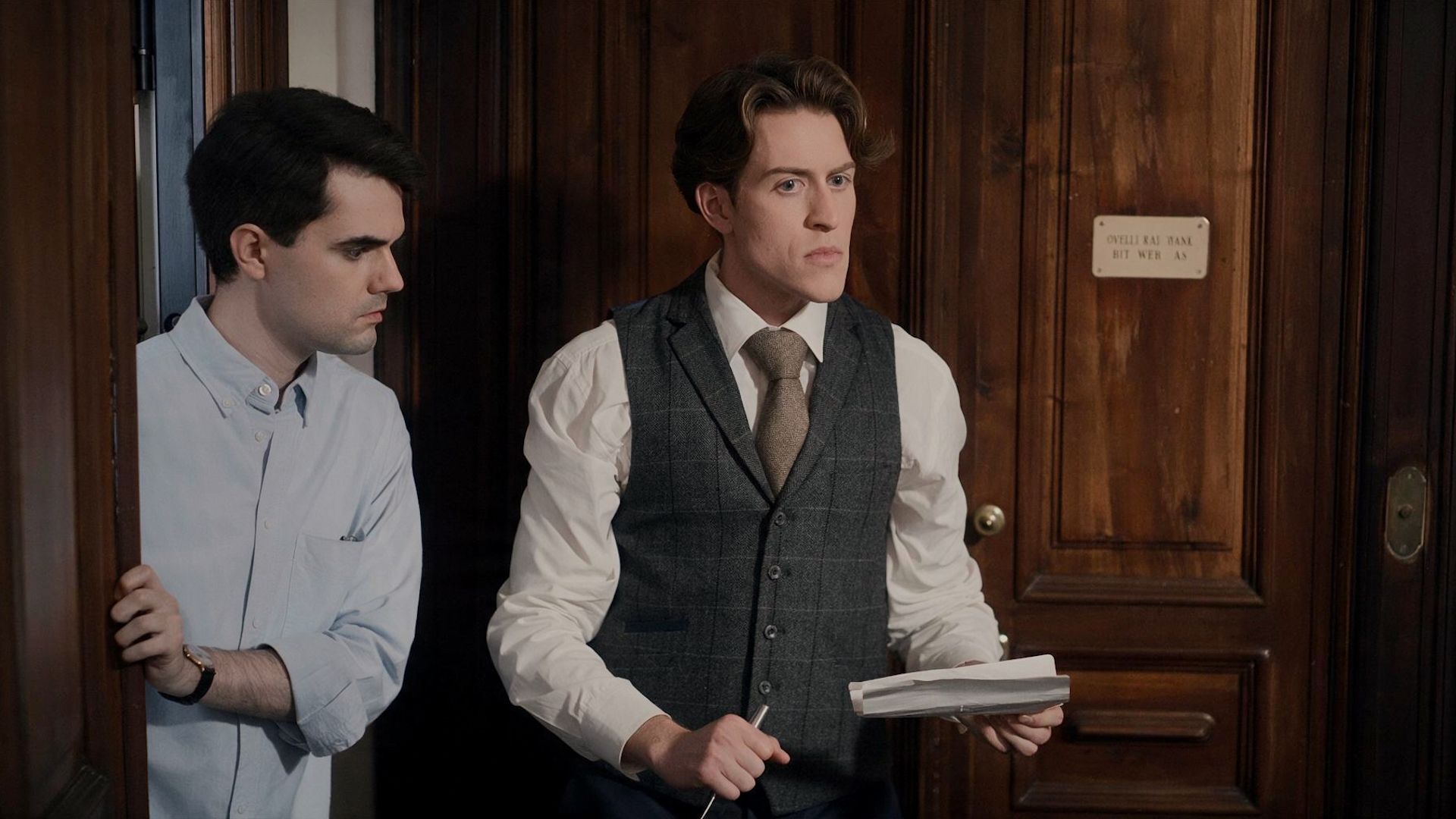 Watson looking at Sherlock, who's holding a pen and paper, in Moriarty Rising