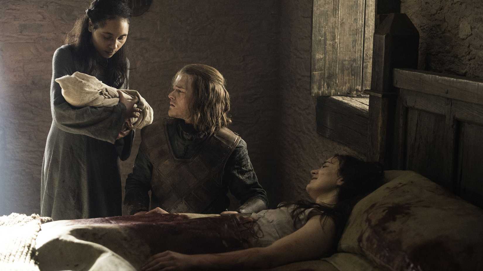 Lyanna (Aisling Franciosi) lying on a bed after giving birth to Jon as Ned Stark (Robert Aramayo) looks at the infant.