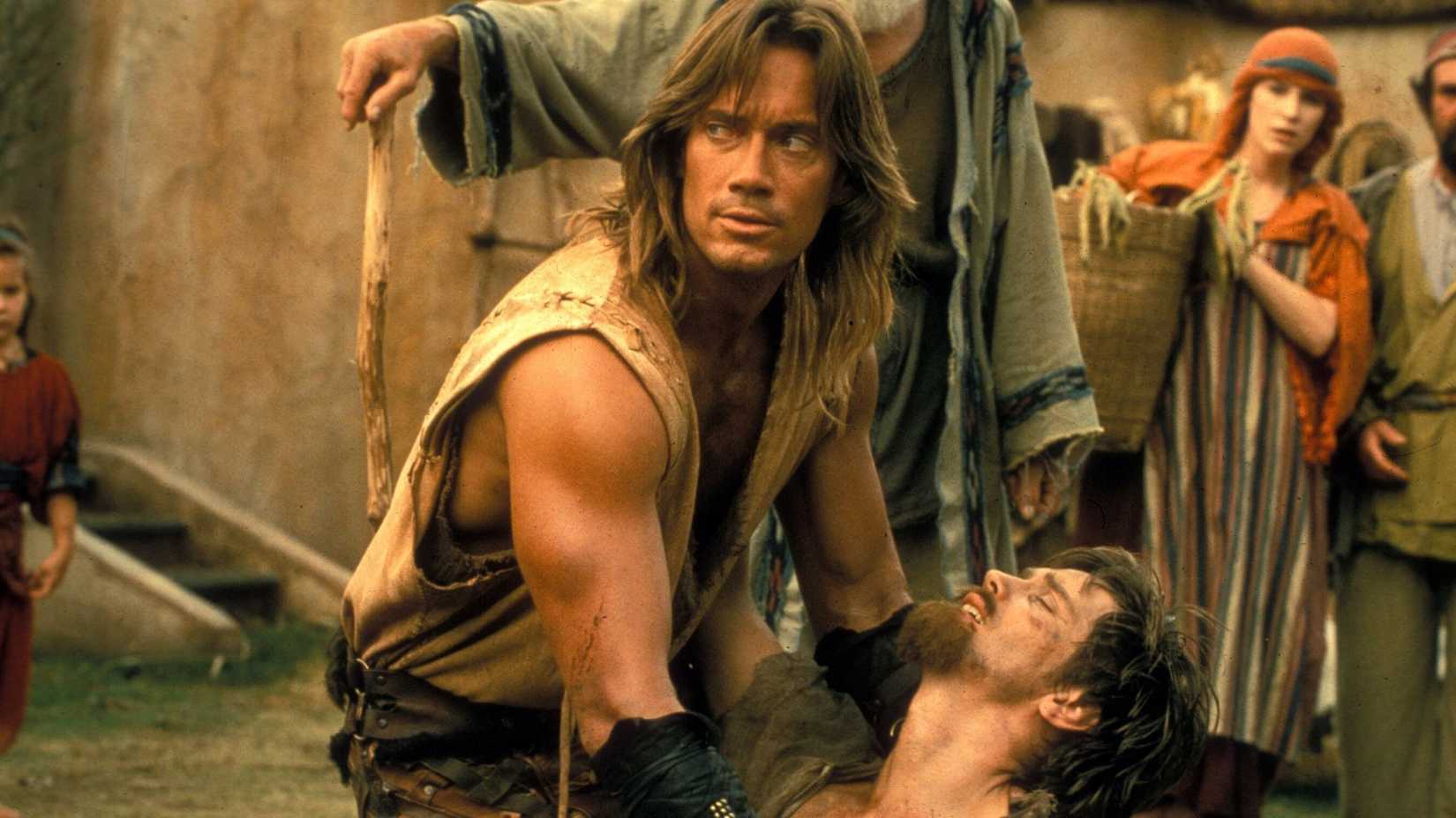 Hercules (Kevin Sorbo) holding up a wounded man in Hercules: The Legendary Journeys.