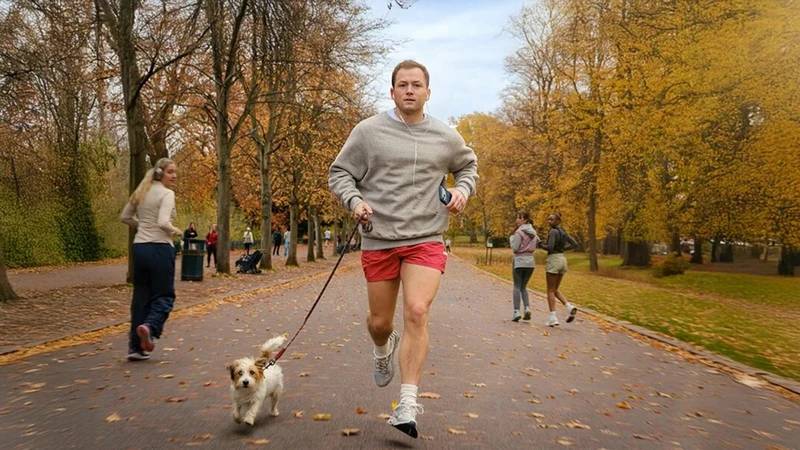 Taron Egerton jogging with his dog as multiple women look back at him