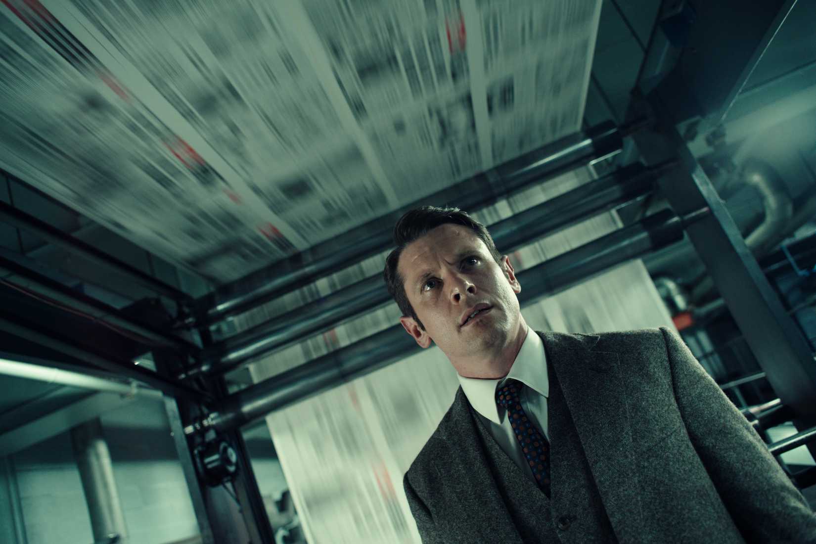 Jack O'Connell in a suit against newspapers being printed in Ink
