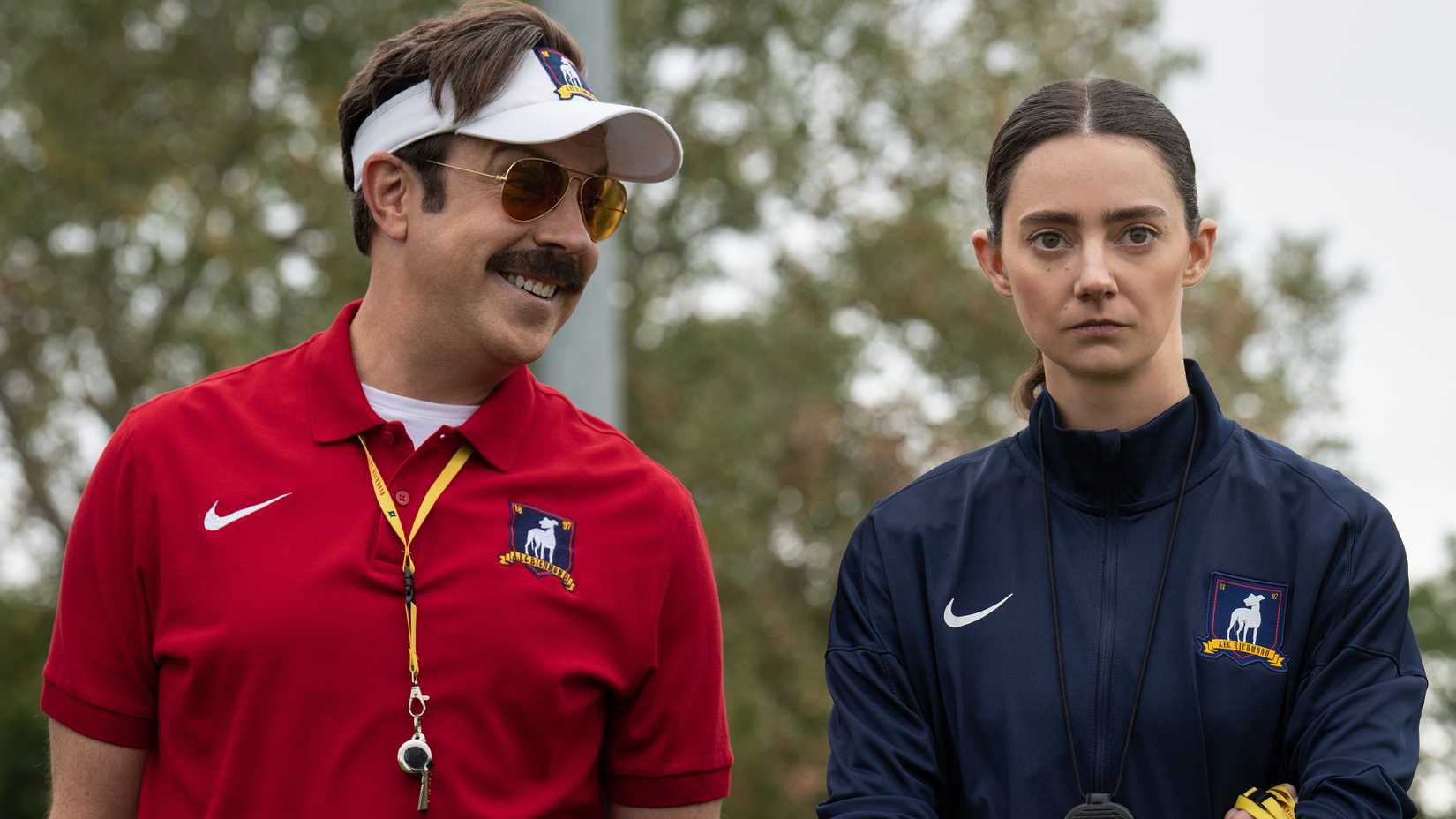 Jason Sudeikis' Ted smiling while talking to Tanya Reynolds' Alice looking unamused in Ted Lasso season 4