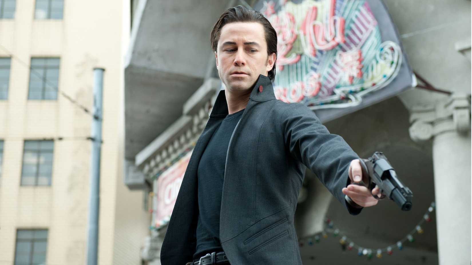 Joseph Gordon-Levitt holding a gun as Joe in Looper