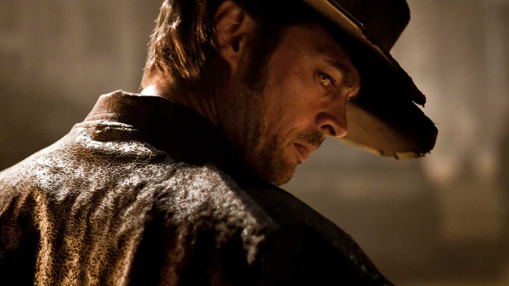 Karl Urban's Black Hat looking intensely over his shoulder in Priest
