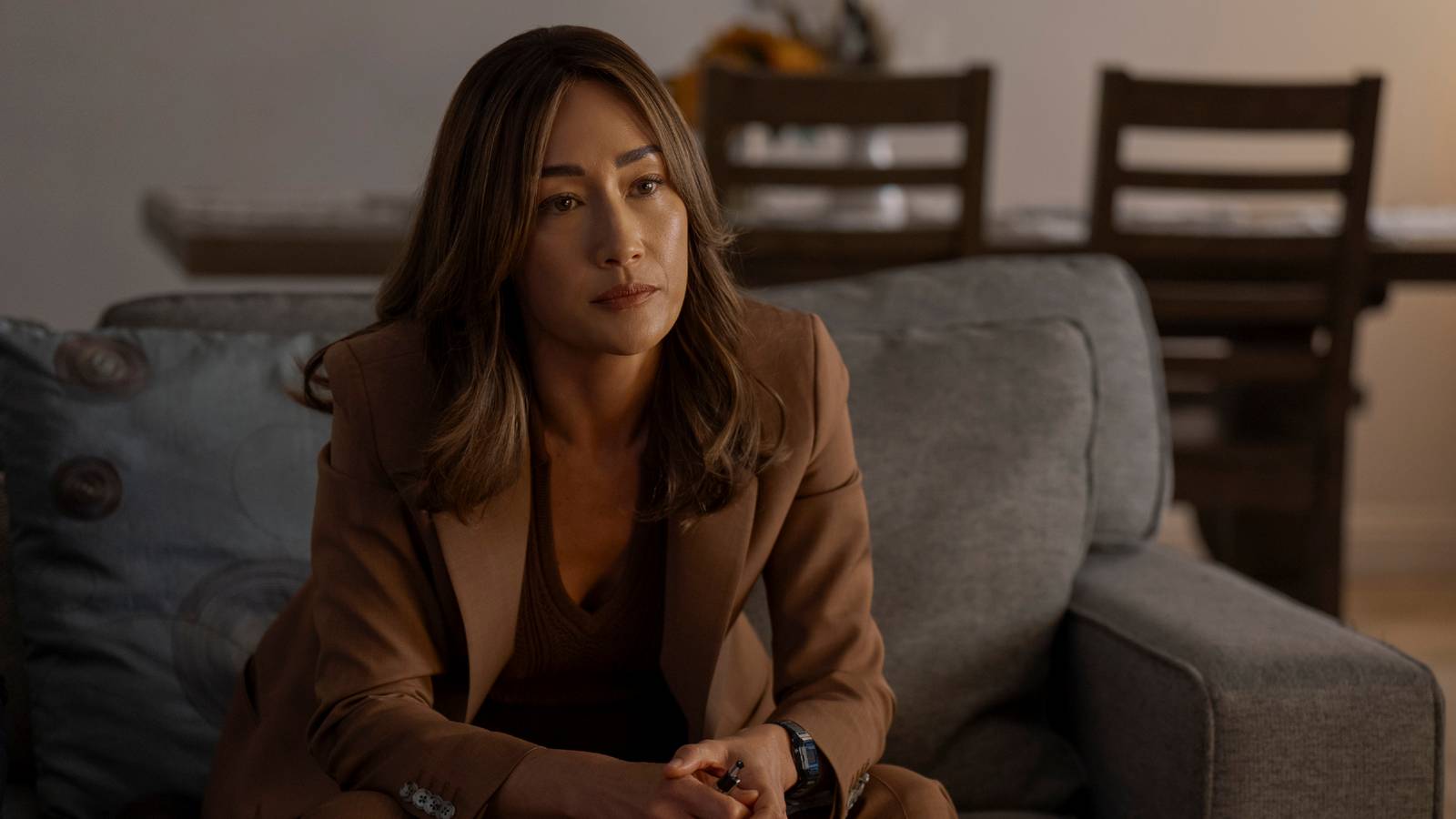 Maggie Q's Renee Ballard sits on a couch in Ballard season 1 episode 5