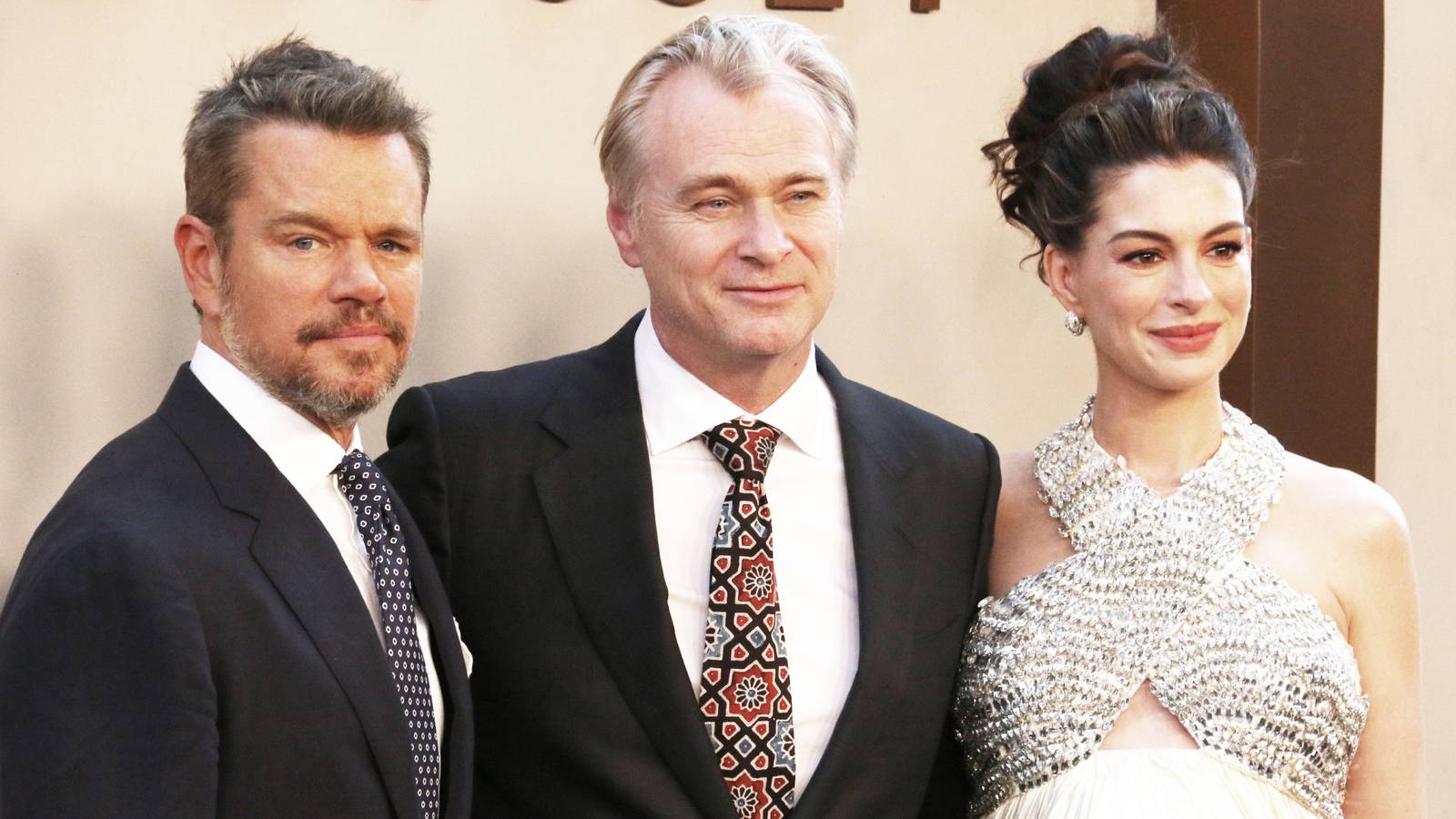 Matt Damon Christopher Nolan and Anne Hathaway posing arm in arm on the red carpet for The Odyssey