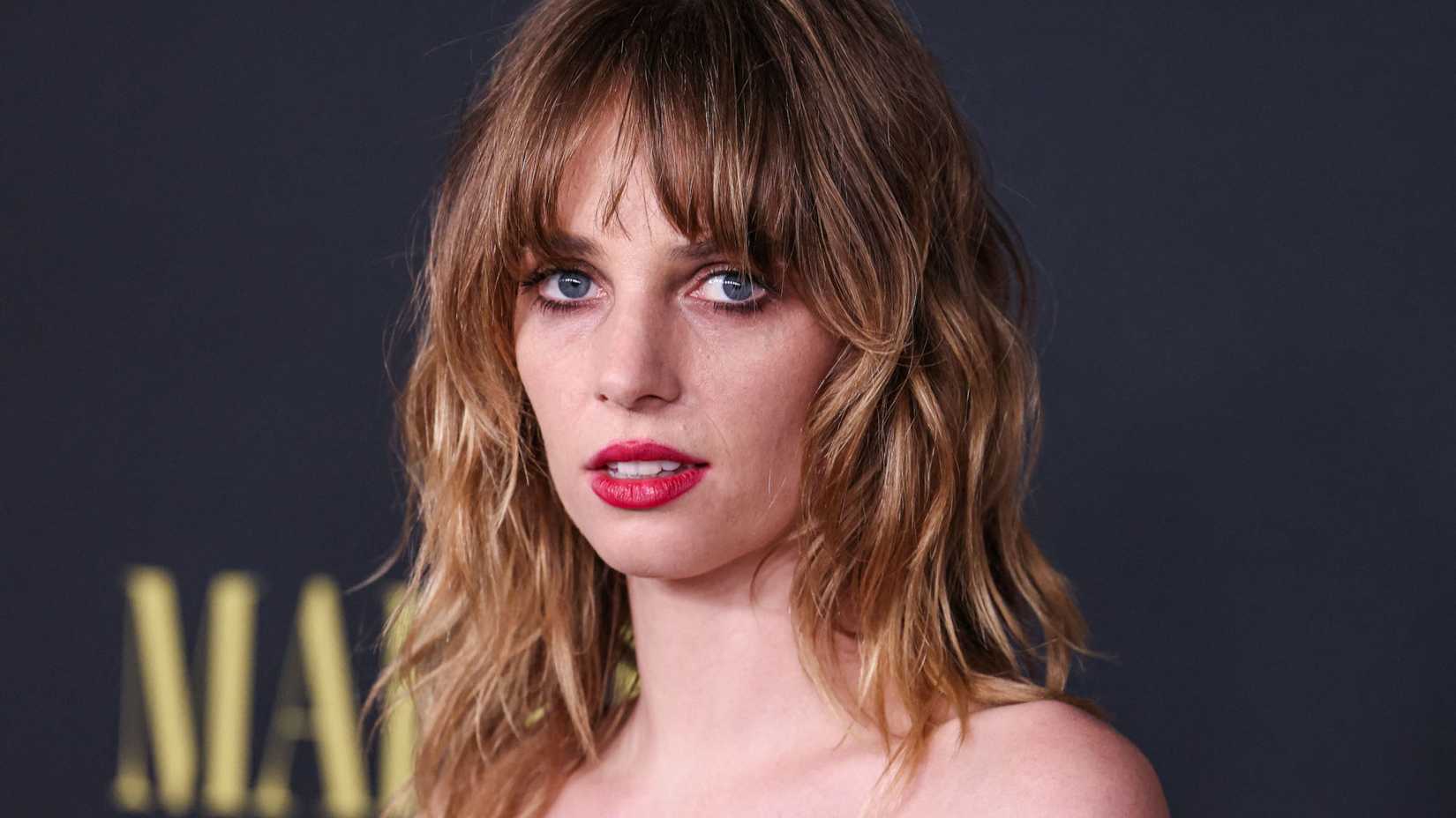 Maya Hawke looks forward with a neutral expression while attending a red carpet