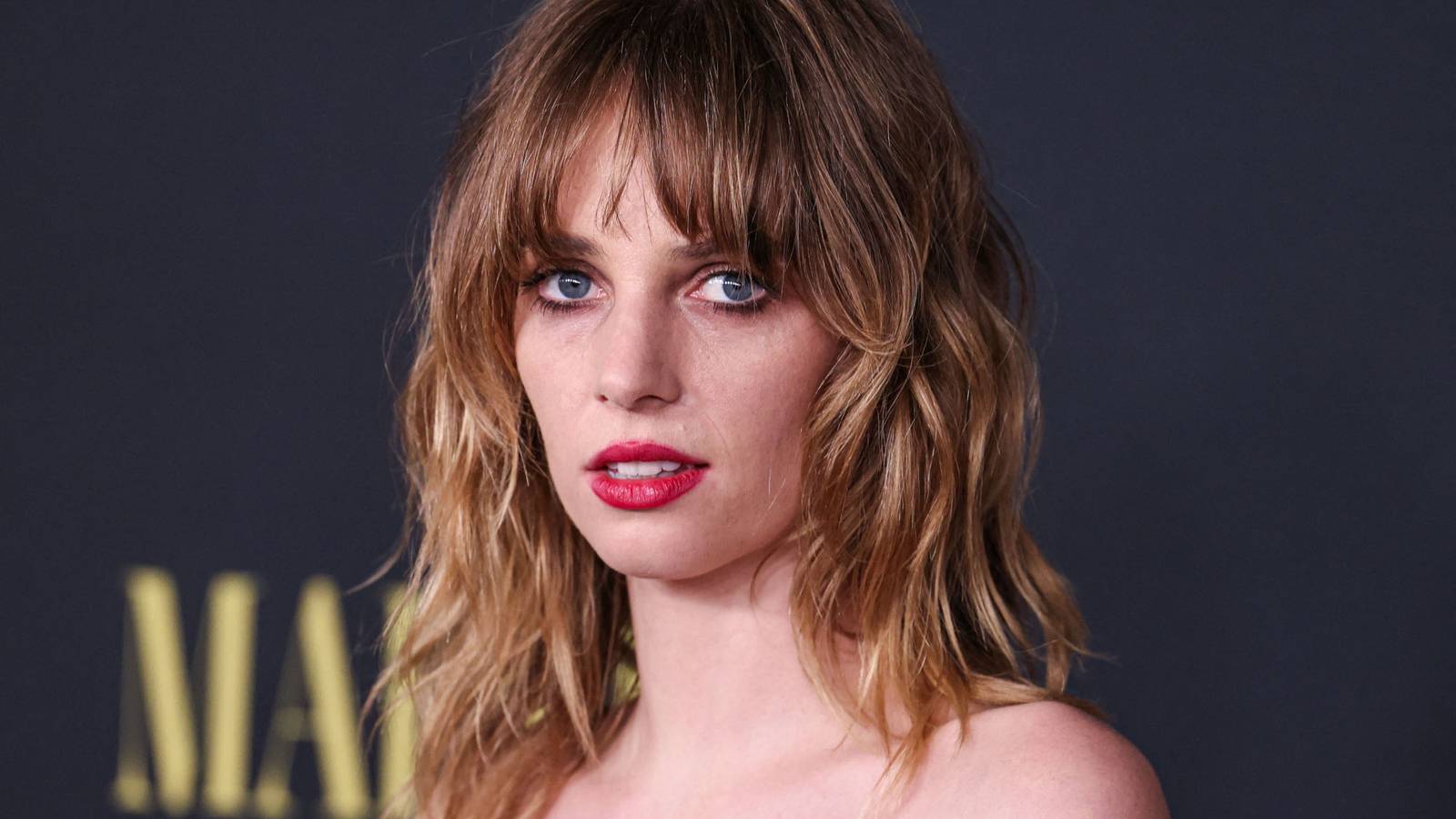 Maya Hawke looks forward with a neutral expression while attending a red carpet
