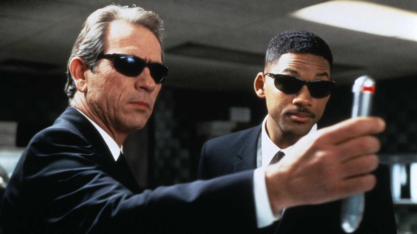 Agent J (Tommy Lee Jones) and Agent Kay (Will Smith) wearing shades while using the neuralizer in Men in Black