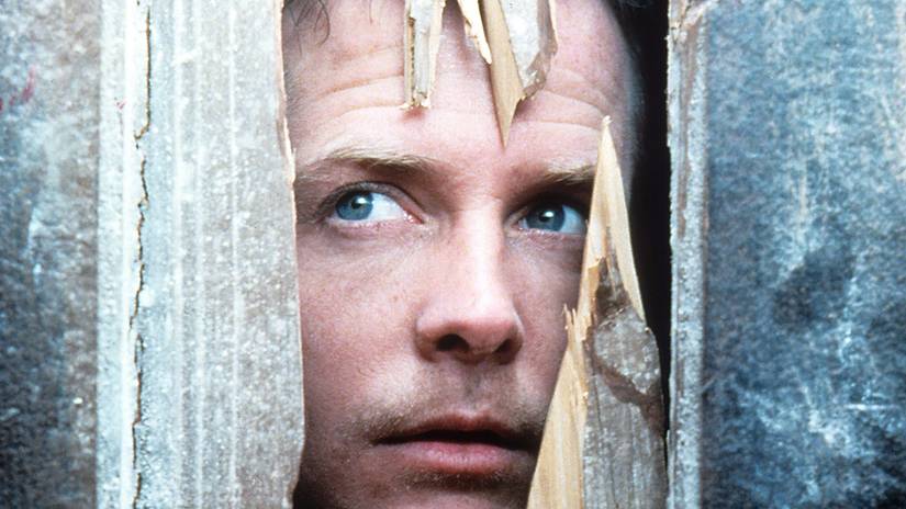 Michael J. Fox's Frank looking through a broken door in The Frighteners