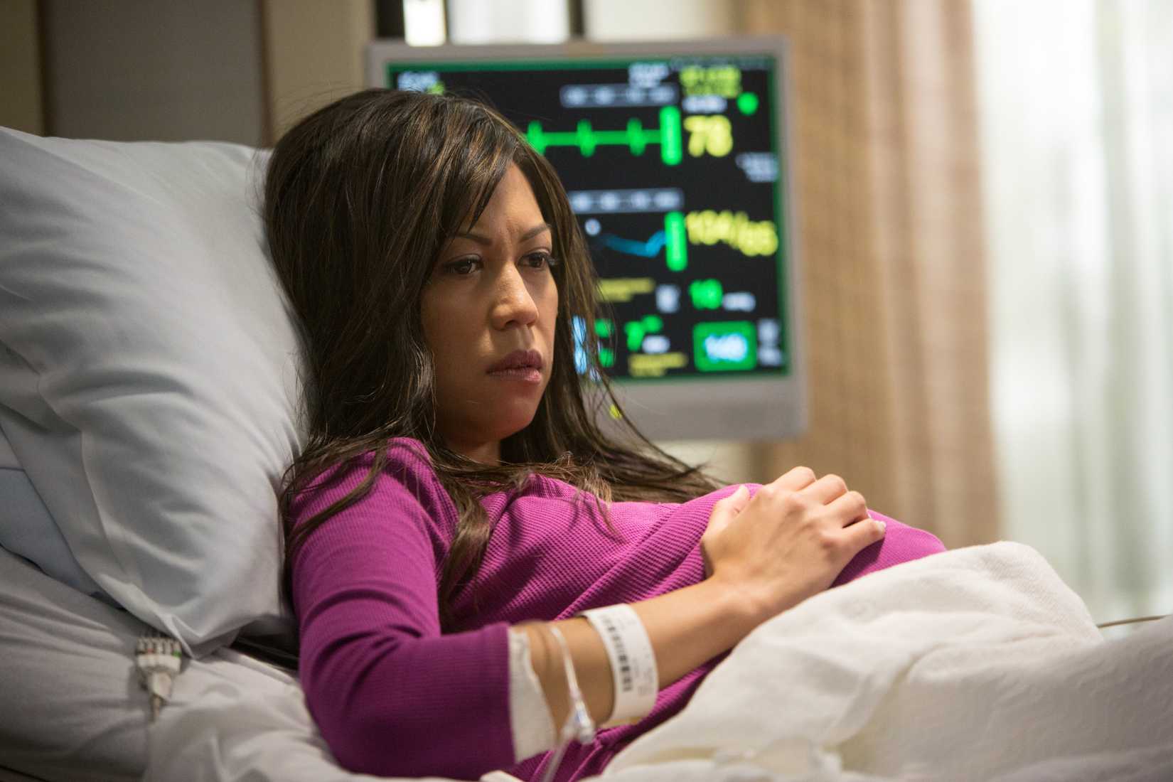 A pregnant Asian woman lays in a hospital bed