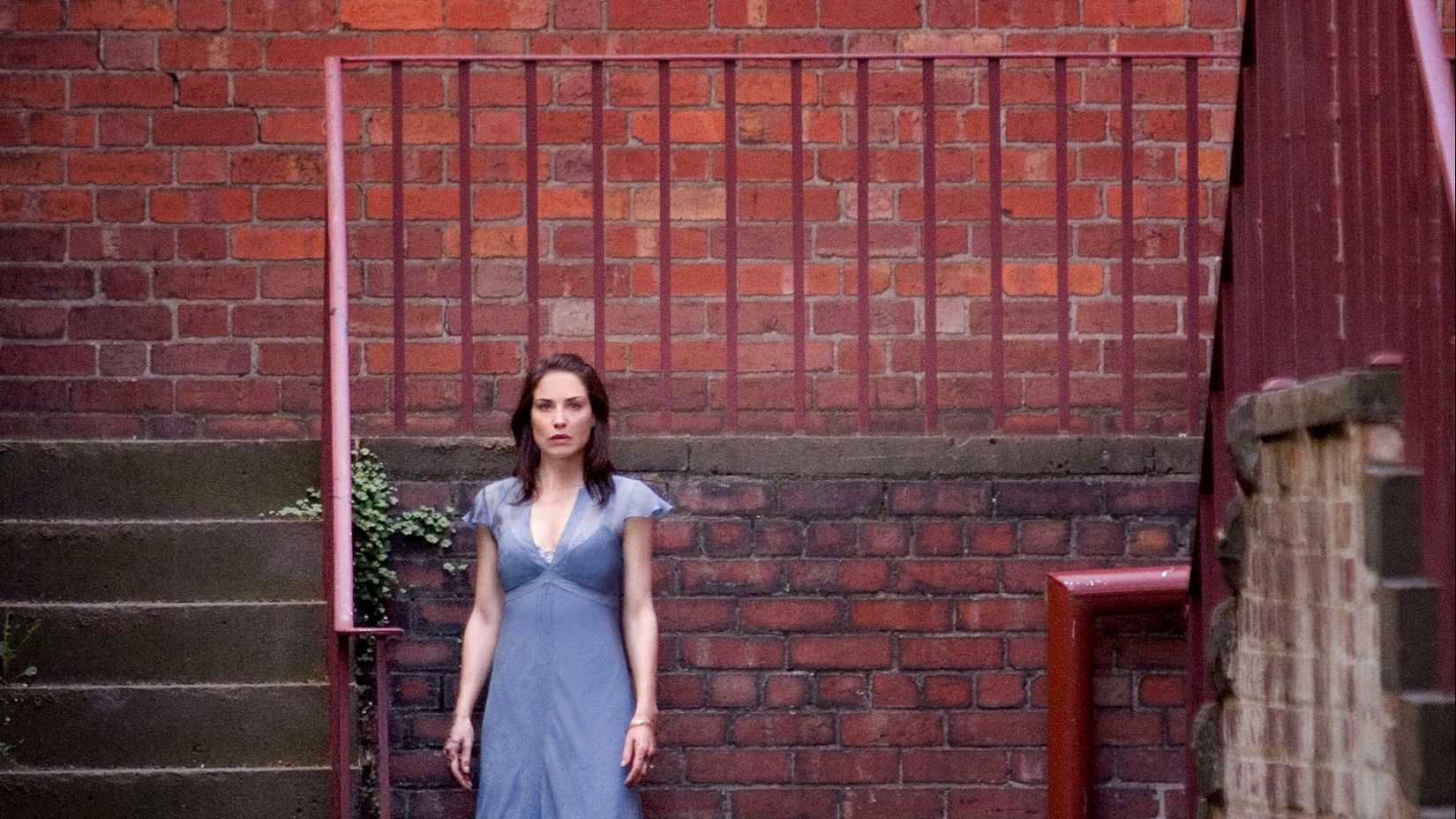 Doris (Claire Forlani) standing with her back to a brick staircase in Nightmares & Dreamscapes: From the Stories of Stephen King.