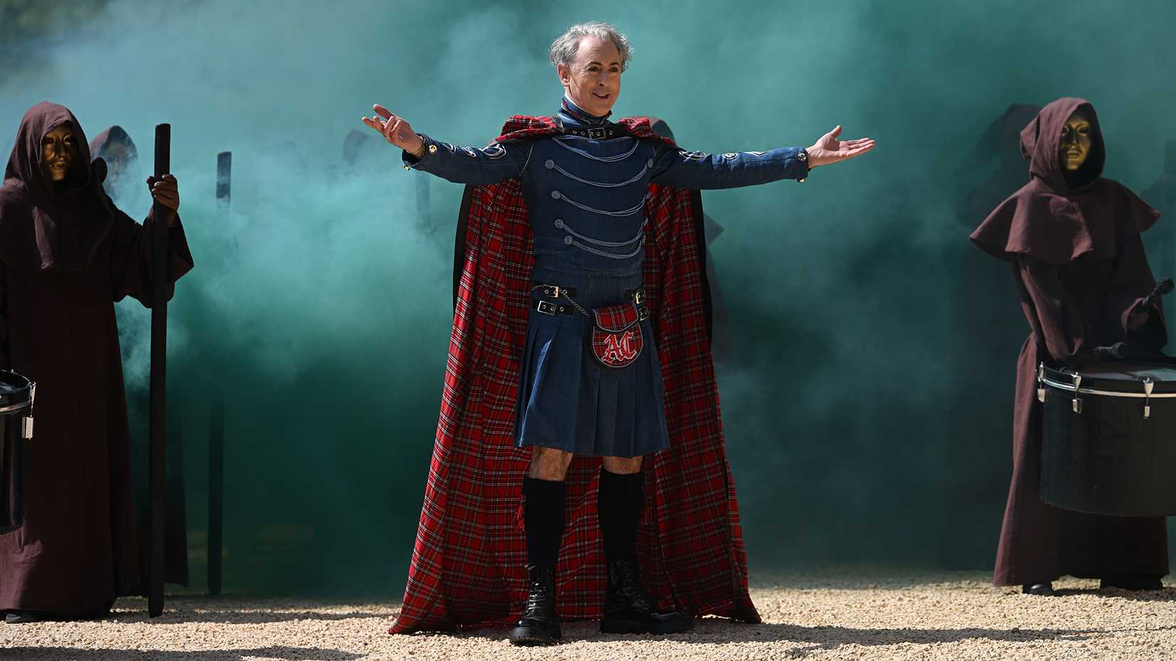 Still of Alan Cumming in front of a wall of blue smoke on The Traitors: New Blood.
