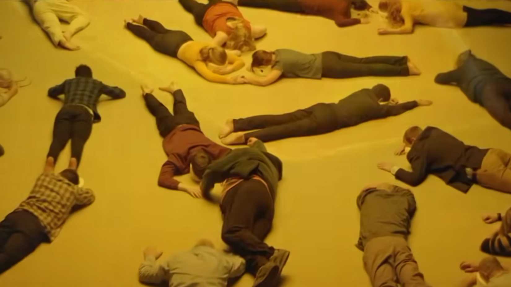 People laying face down in a yellow room in Aniara