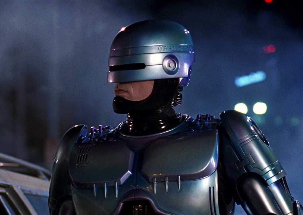 RoboCop standing outside at nighttime next to a car