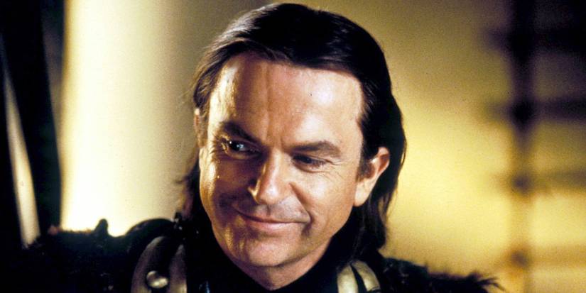 Sam Neill as Merlin smiles and looks to the side in the 1998 Merlin miniseries