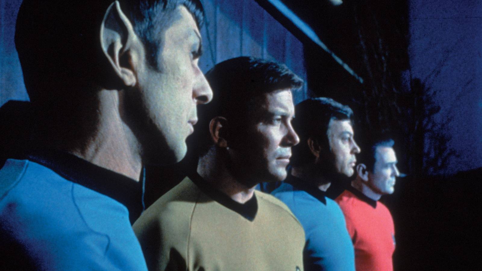 Spock, Captain Kirk, Bones, and Scotty stand next to each other looking to the right in Star Trek The Original Series