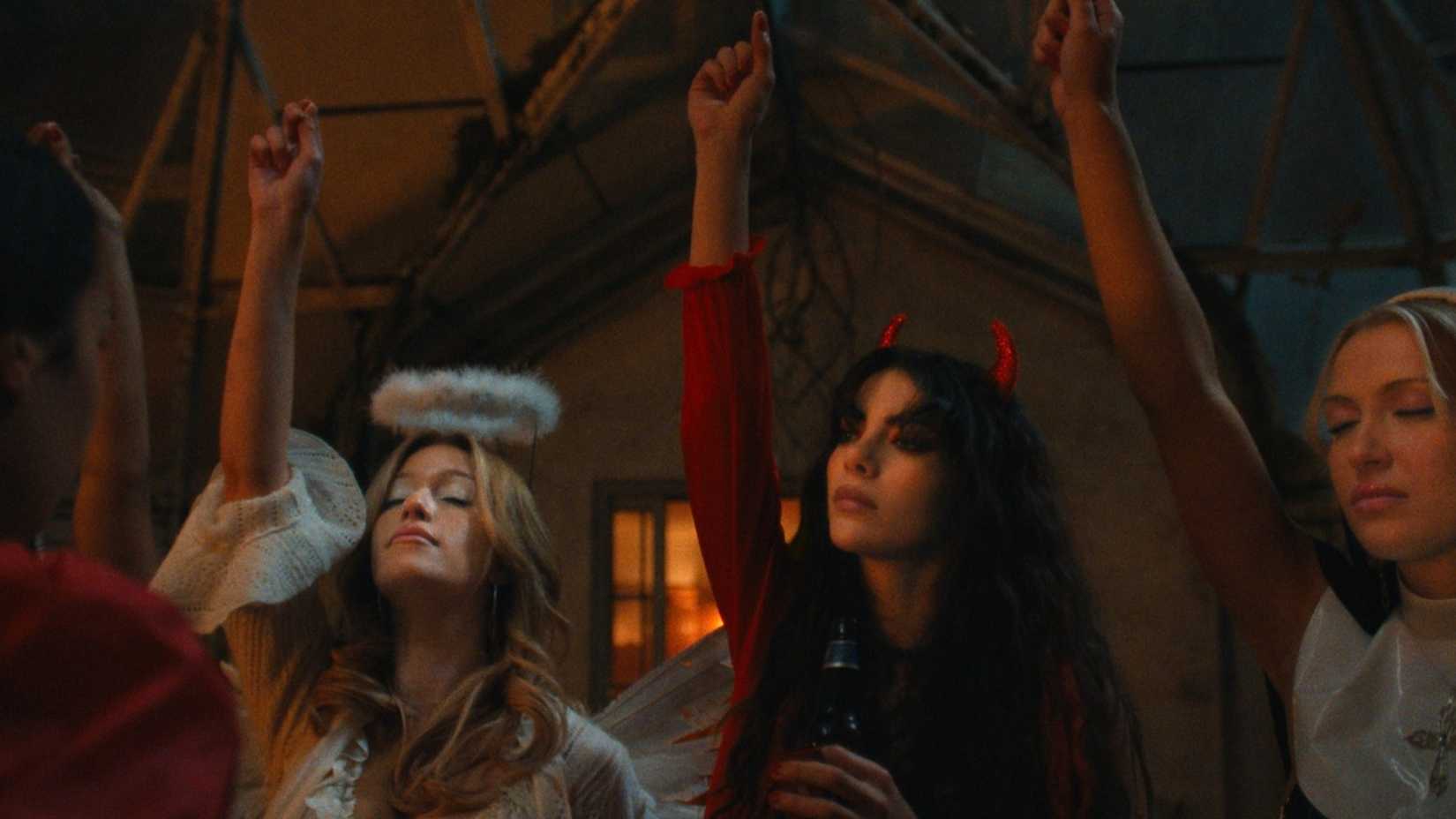 Teenage girls in angel and devil costumes with their hands raised in Netflix's The Body