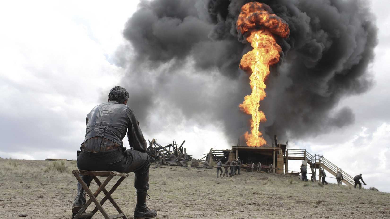 Daniel Plainview (Daniel Day-Lewis) looking out at a stream of oil engulfed in flame spouting from the ground in There Will Be Blood