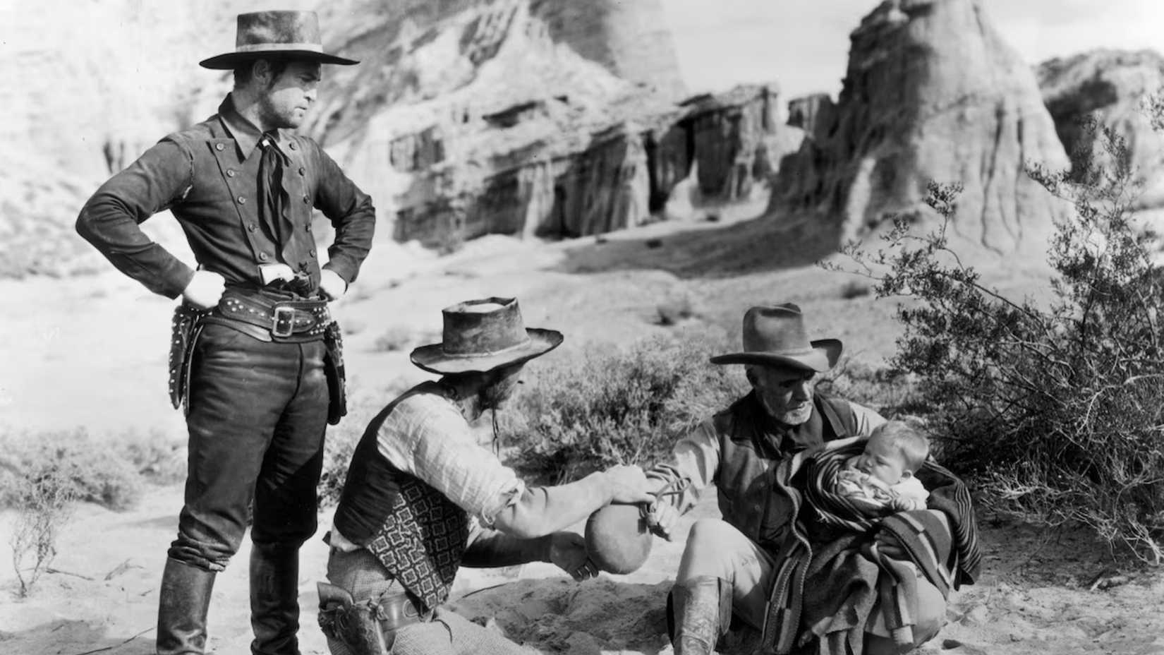Three men tend to a baby in the desert in Three Godfathers