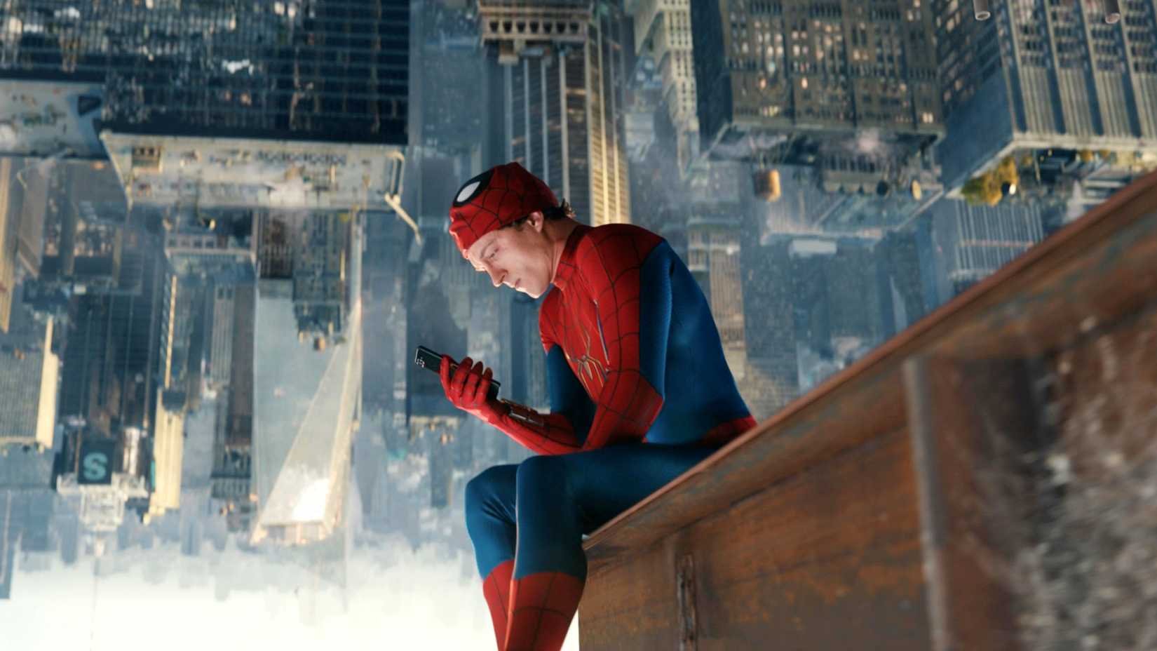 Tom Holland as Peter Parker checking his phone upside down on a building in Spider-Man Brand New Day