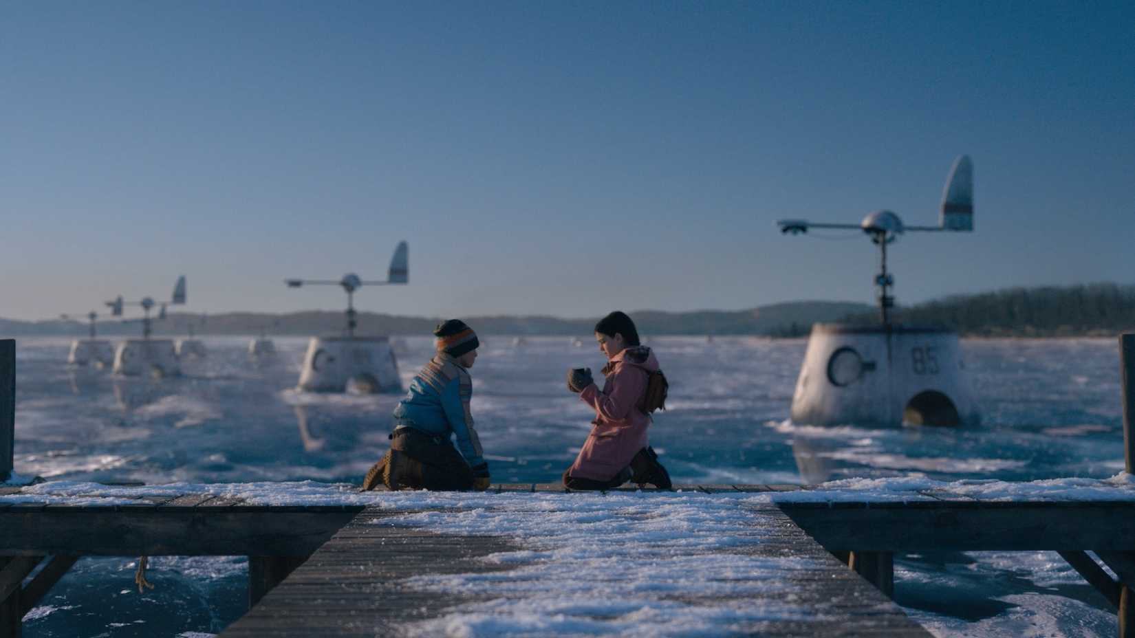 Two children sit beside machines in an icy expanse from Tales from the Loop 2020