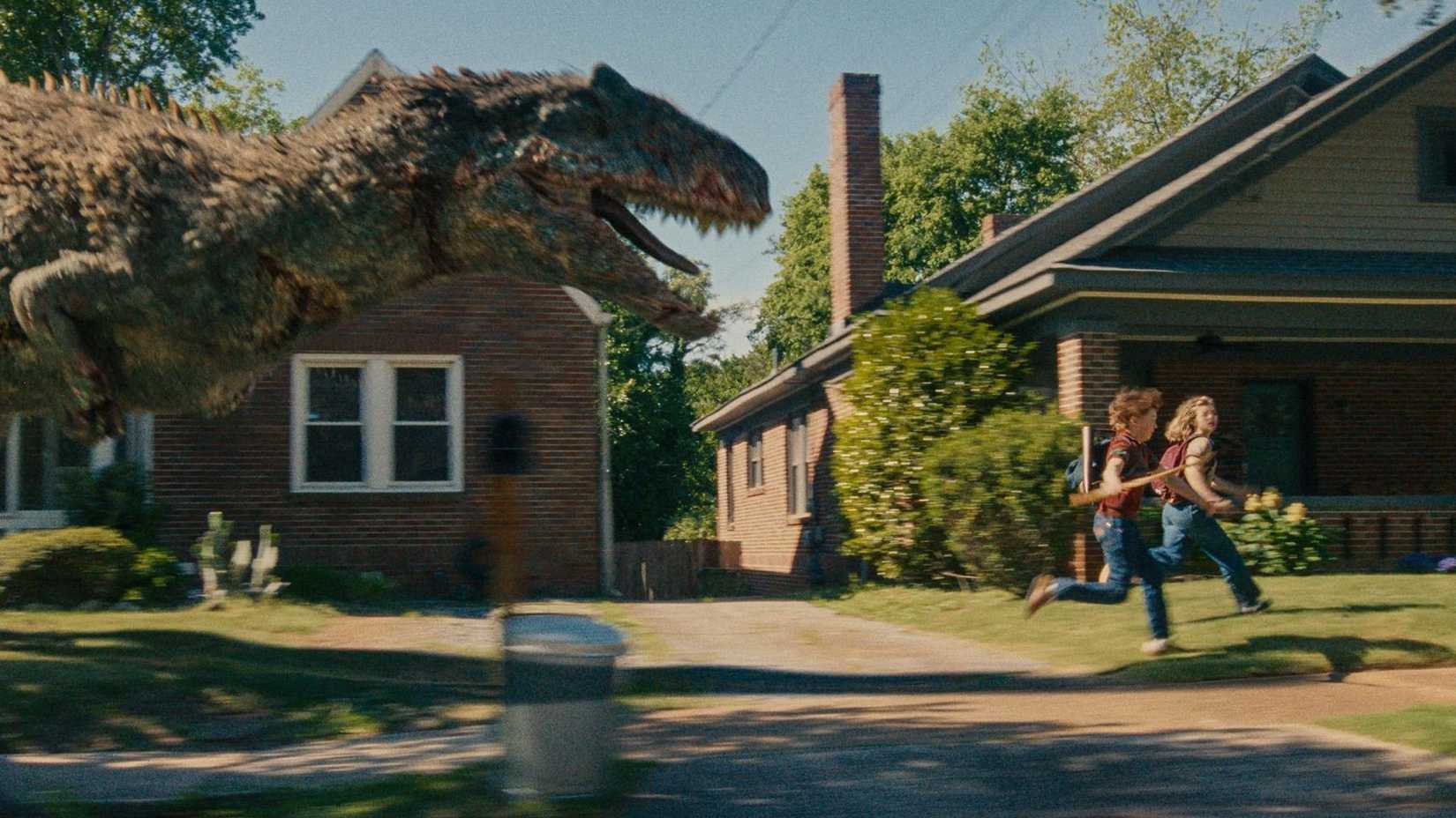 A dinosaur chasing two children down a suburban street