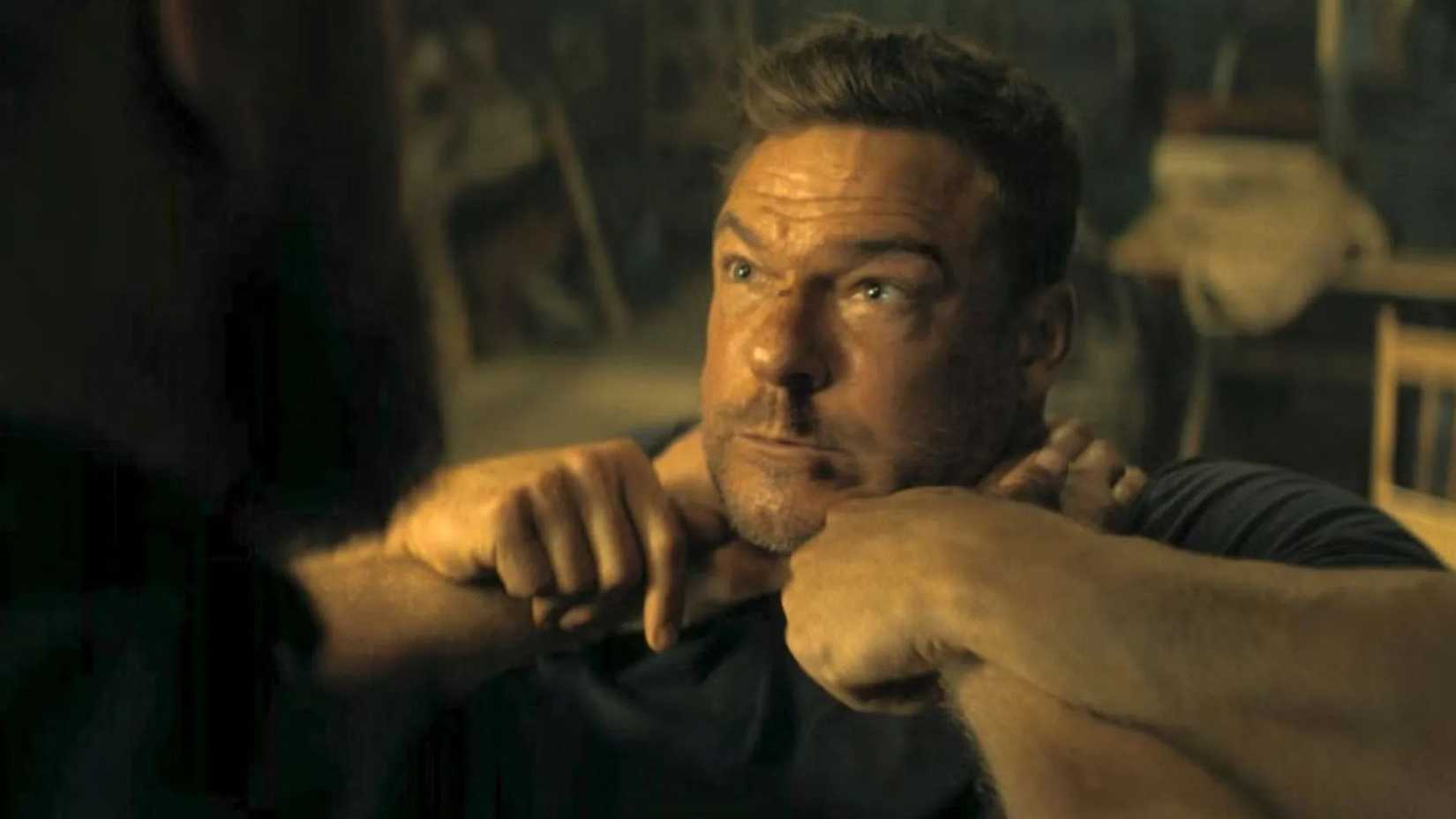 Paulie with his hards around Reacher's neck as Reacher struggles