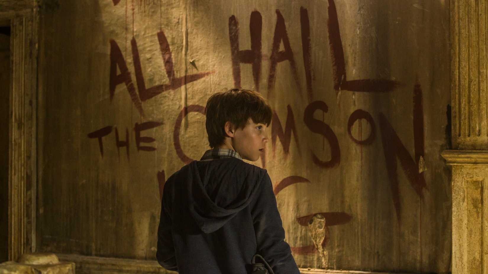 Jake Chambers in The Dark Tower movie, looking at writing on the wall that says "All hail the Crimson King"