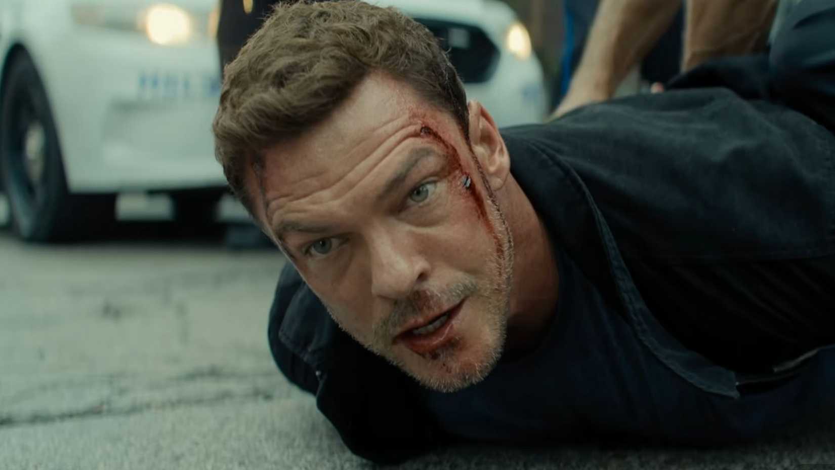 Reacher with a bloodied face, looking at something ahead of him