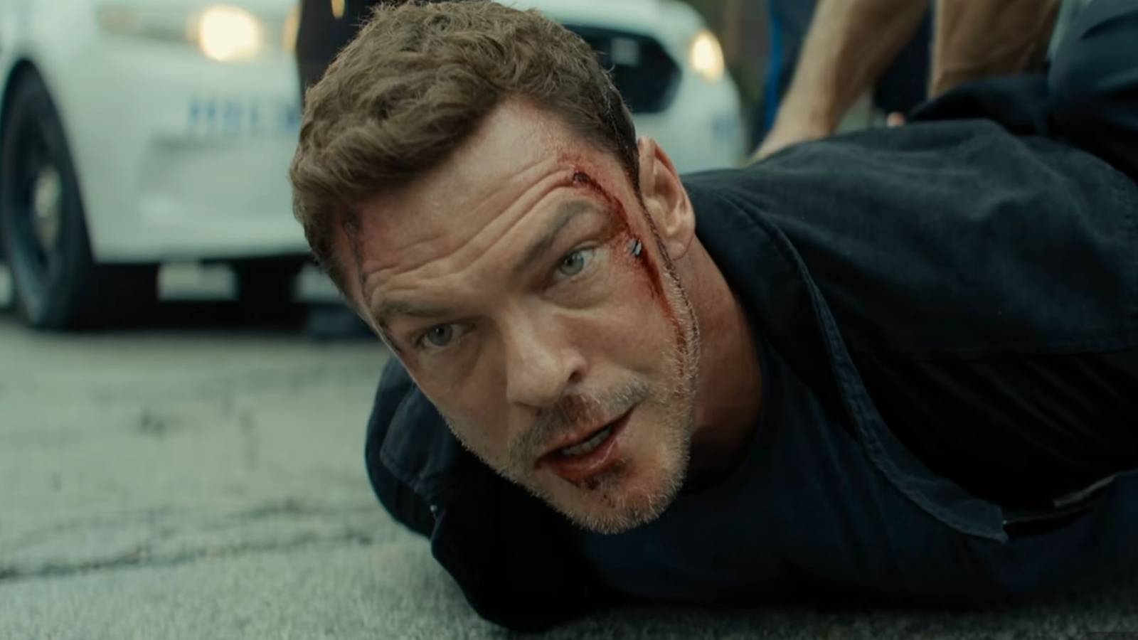 Reacher with a bloodied face, looking at something ahead of him