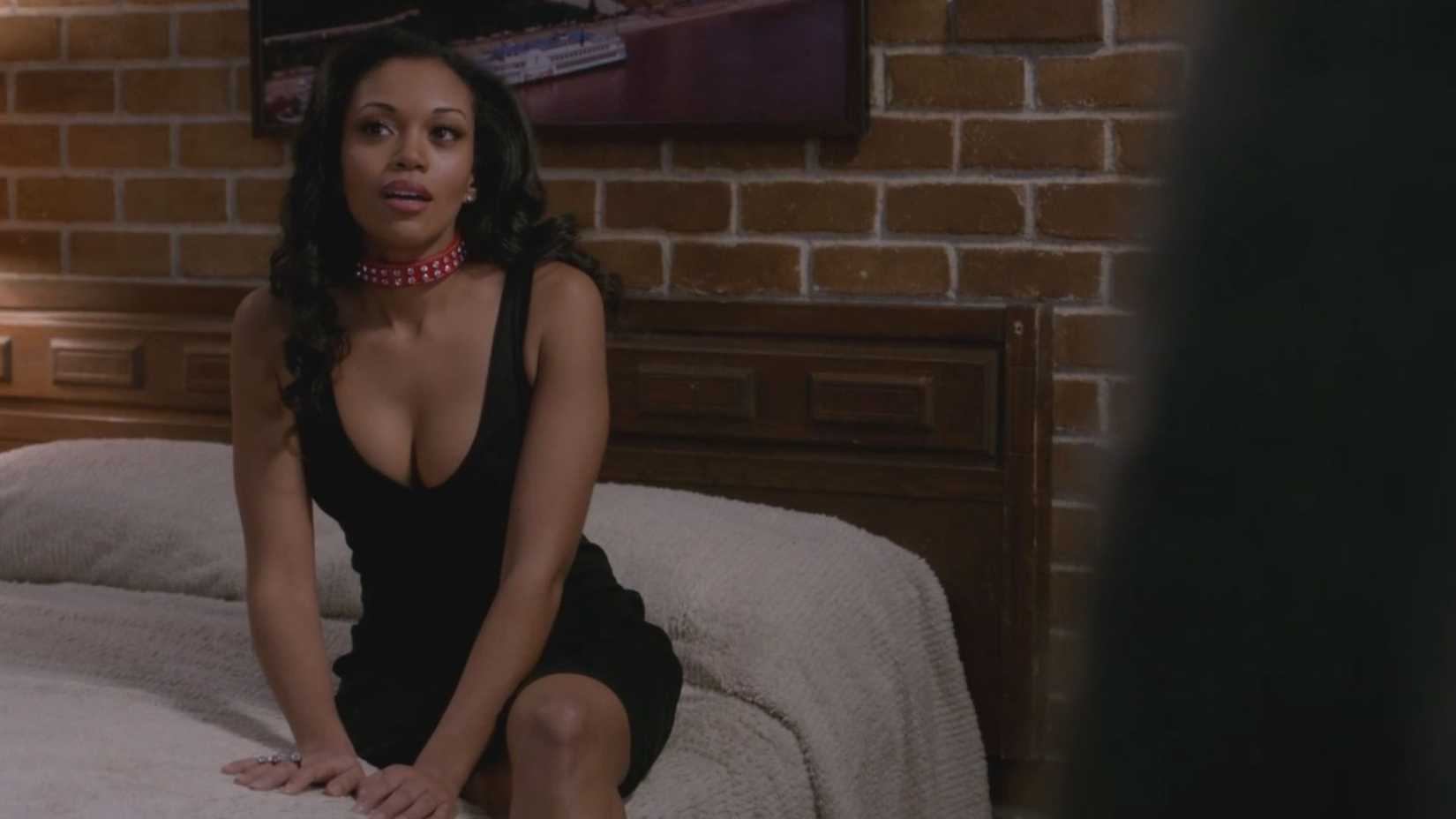 A Black woman sits on a bed wearing a dog collar in an episode of Supernatural
