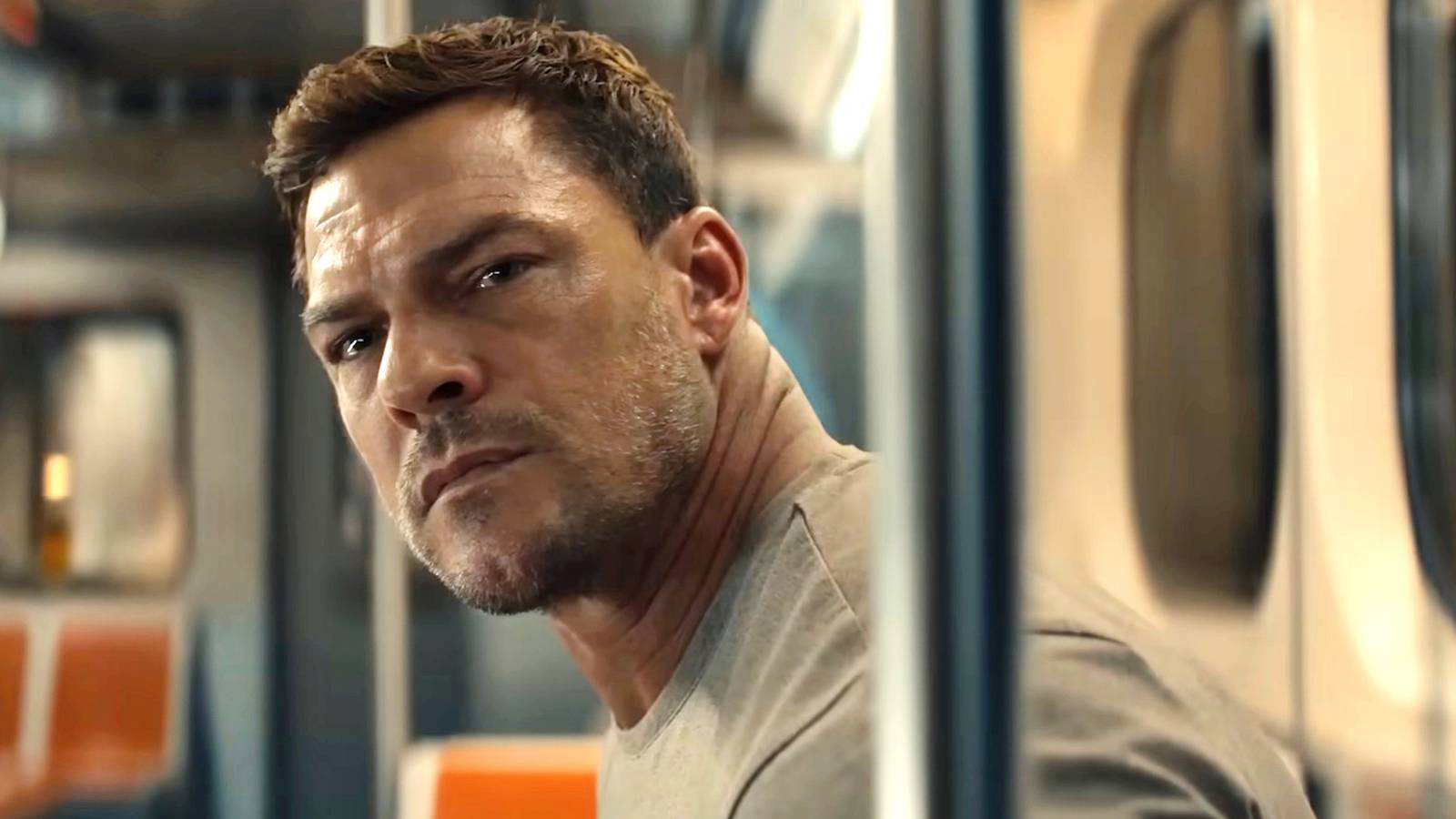 Alan Ritchson’s Jack Reacher looking at a woman in a train Reacher season 4’s opening scene