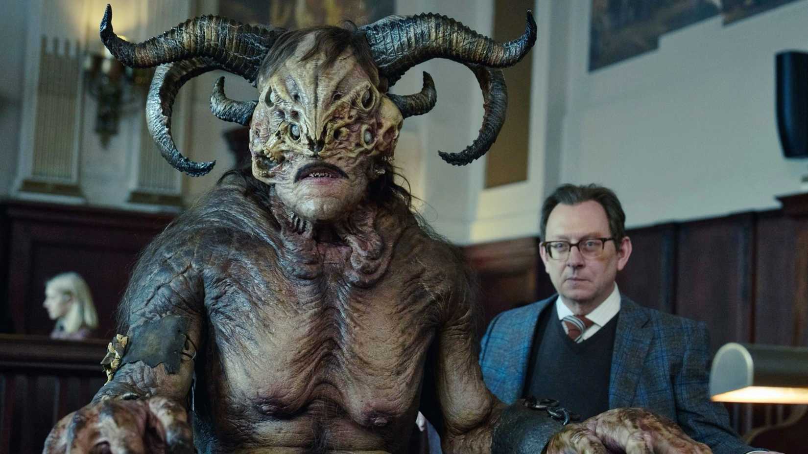 Michael Emerson and Fedor Steer’s characters sitting in a courtroom in Evil