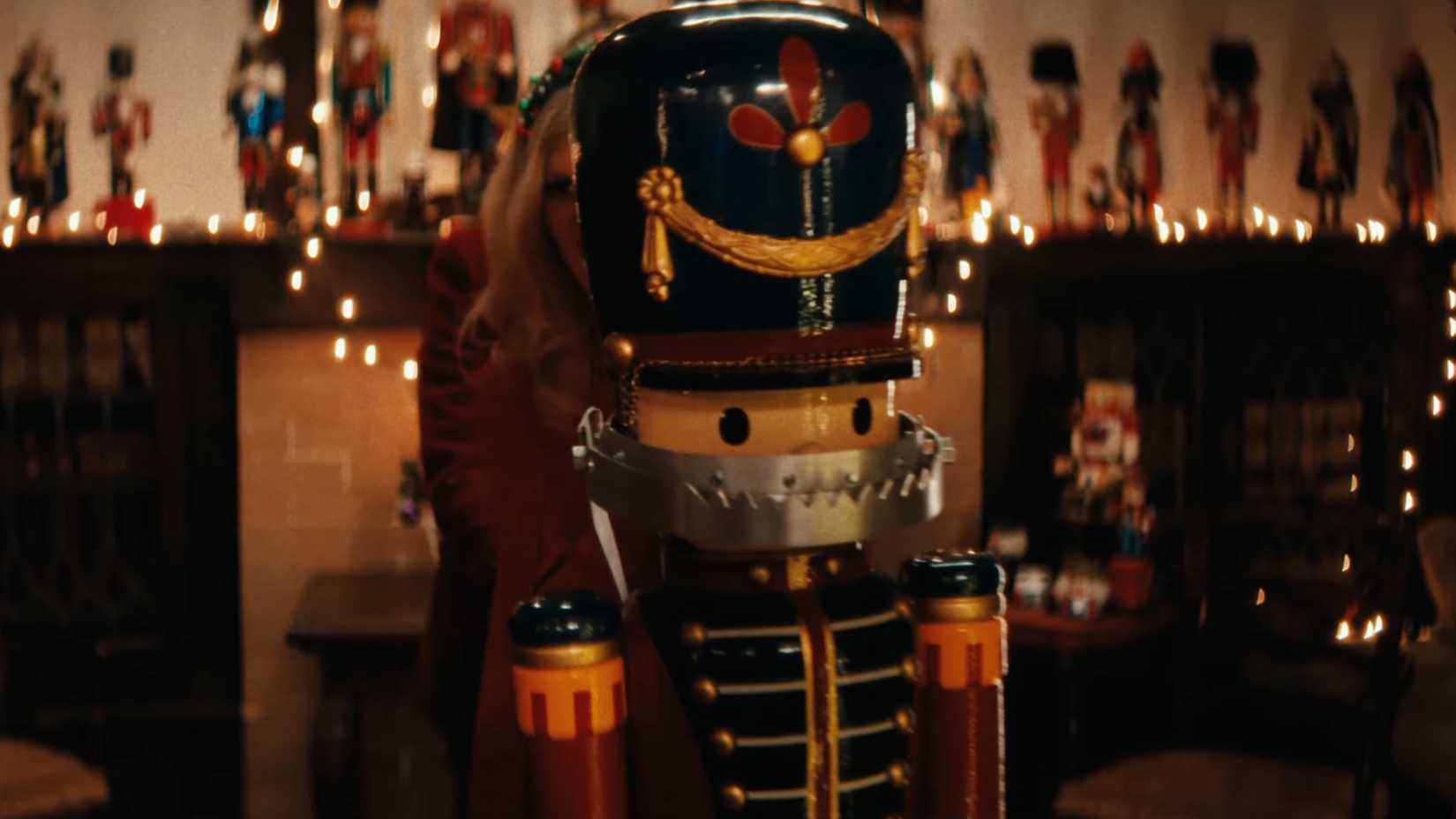 A big nutcracker statue with a bear trap for a mouth with someone behind it in Christmas At The Kringles