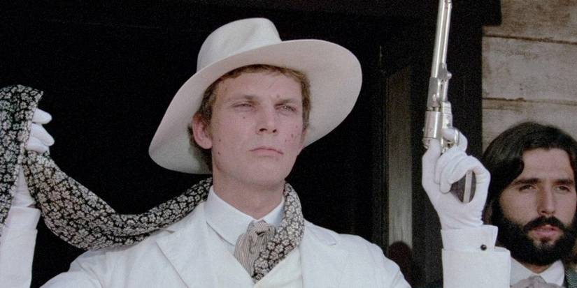 A man in a white suit holds up a pistol in The Grand Duel