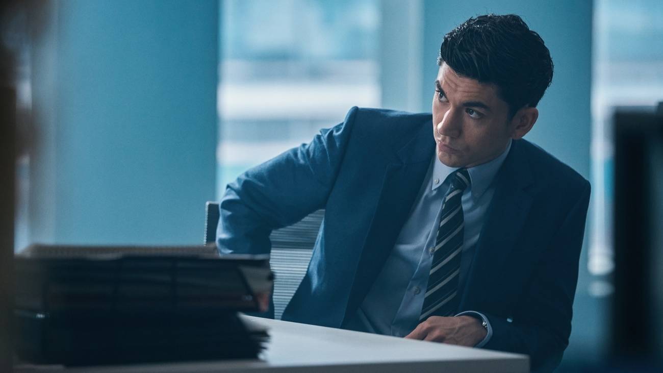 Johnny sits as a desk looking nervously to the side in HBO's War
