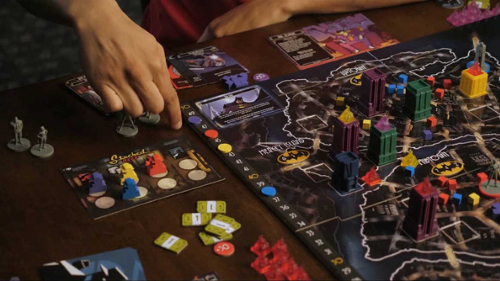 Someone moving a piece in the Batman: Enemies of Gotham City board game.
