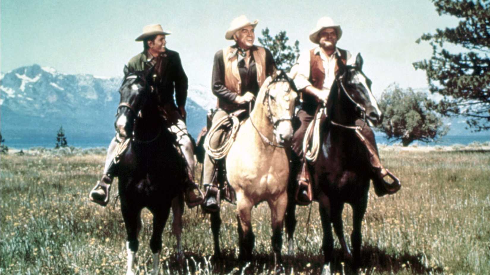 The Cartwrights riding horses through a field in Bonanza.