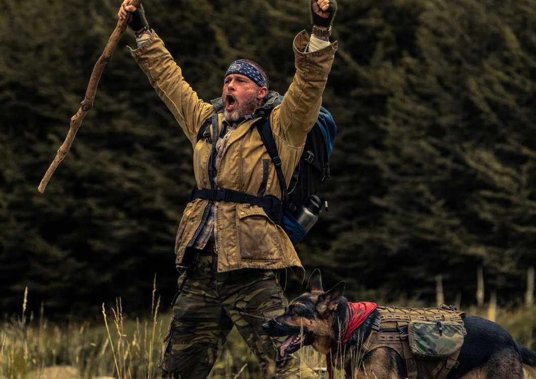 Brad Pitt celebrating with his hands in the air and Odin by his side in Heart of the Beast