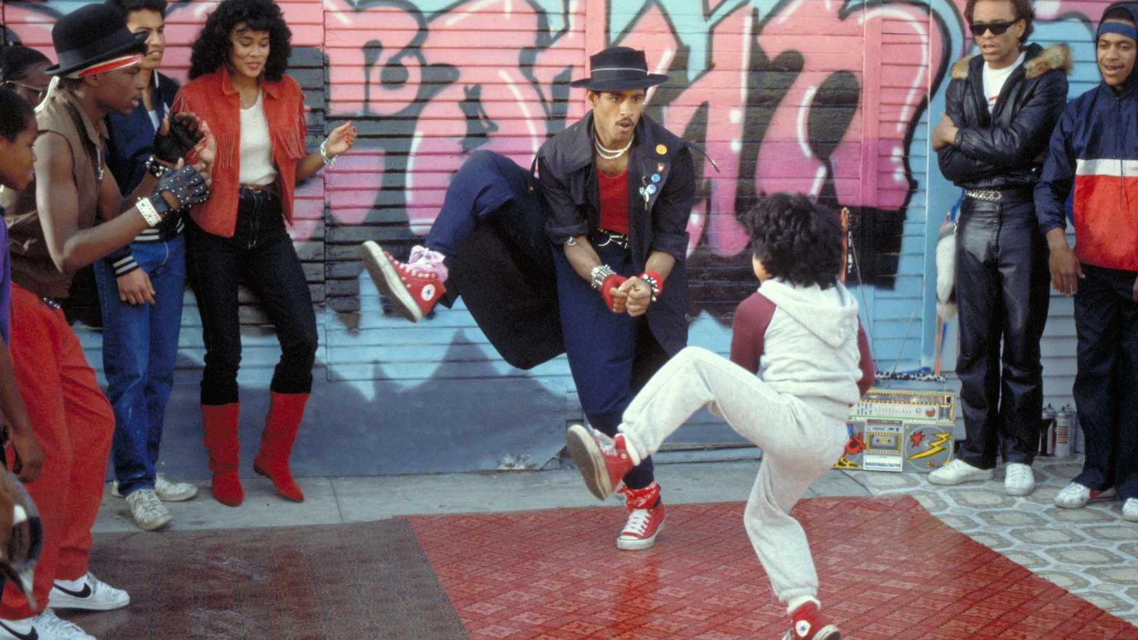 A man and a kid breakdancing in front of a crown in Breakin' 2: Electric Boogaloo.