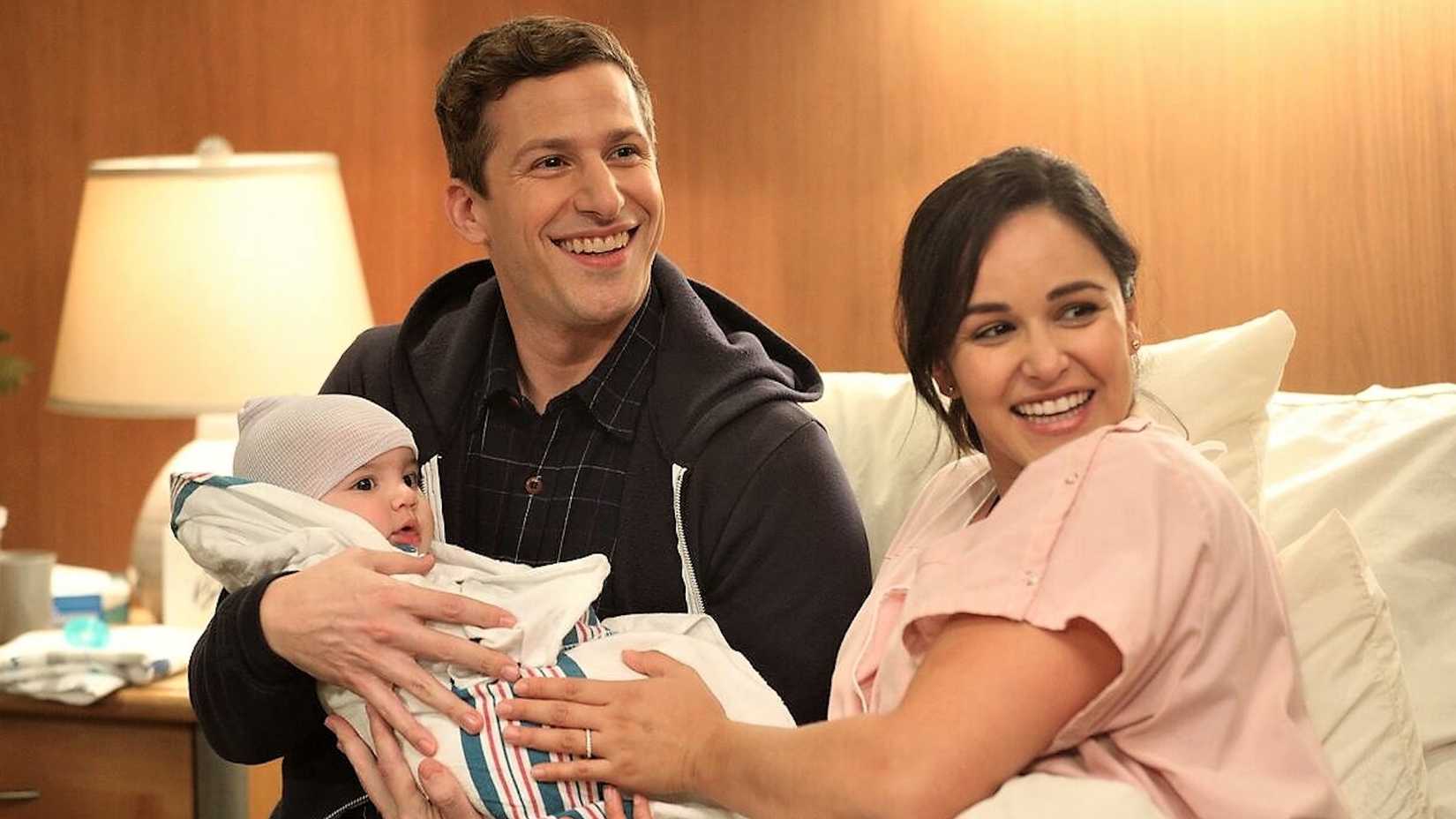 Jake and Amy holding baby Mac in Brooklyn Nine-Nine.